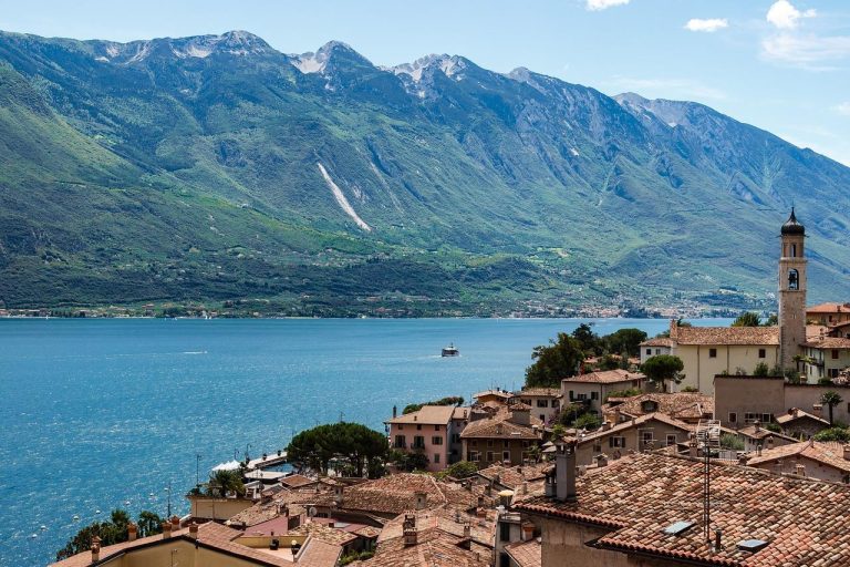 Over ons Camping bij het Gardameer met glimmend water, bergen en sfeervolle Italiaanse architectuur omgeven door olijfbomen en groene